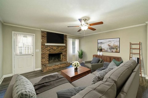 A living room with a grey couch and a fireplace.