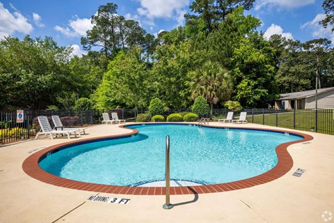 A small pool surrounded by a fence and trees.
