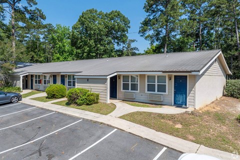 A small building with a blue door is surrounded by a parking lot.