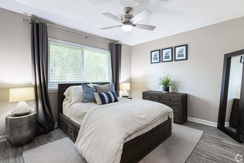 A bedroom with a large bed, a ceiling fan, and a window with curtains.