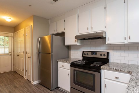A kitchen with white cabinets and a stainless steel refrigerator.