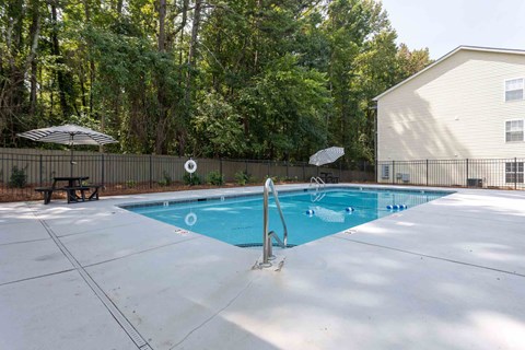 A swimming pool with a diving board and a fence around it.