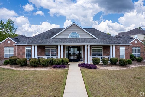 A brick house with a large front porch and a walkway leading to the entrance.