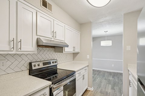 A kitchen with white cabinets and a black stove top oven.
