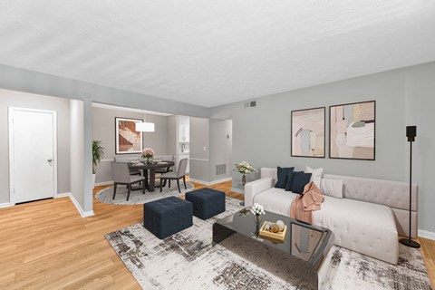 A living room with a white couch, a coffee table, and a dining table with chairs.