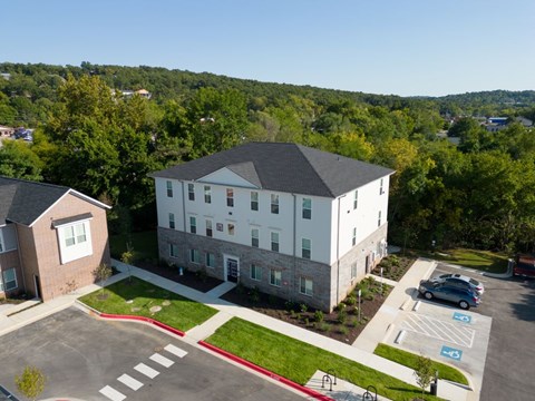A parking lot in front of a large building with a hill in the background.