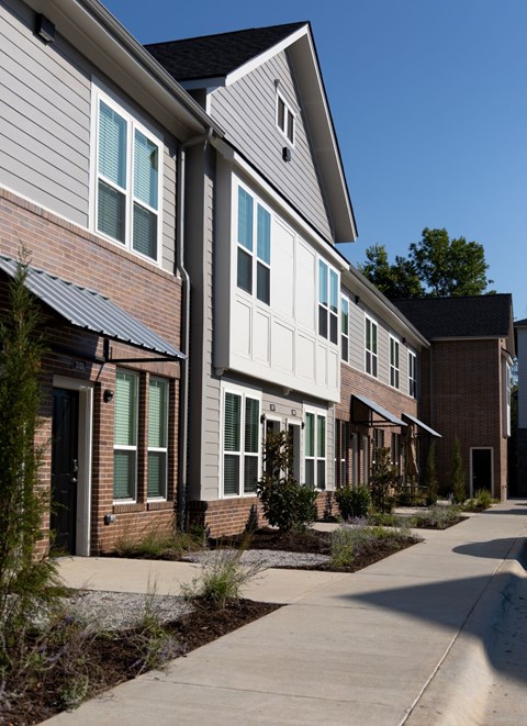 A row of houses with a sidewalk in front.
