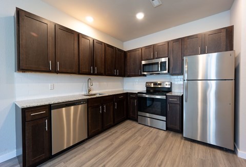 A kitchen with dark wood cabinets and stainless steel appliances.