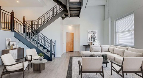 A living room with a staircase and furniture.