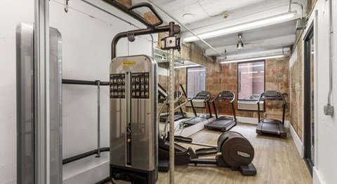 A gym with treadmills, elliptical machines, and a weight machine.
