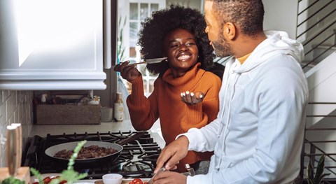 A man and woman are cooking together in a kitchen.