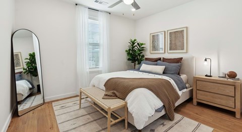 A bedroom with a bed, nightstand, and a mirror.