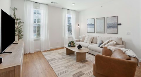 A living room with a white couch, a brown chair, a wooden table, and a flat screen TV.
