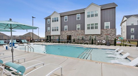 A large swimming pool in front of a multi-story residential building.