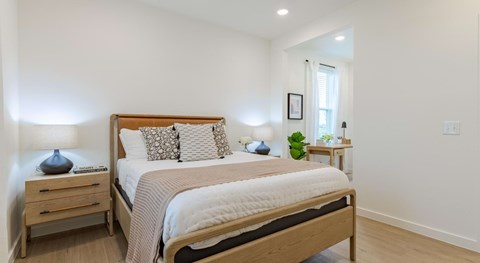 A bedroom with a bed, nightstand, and lamp.