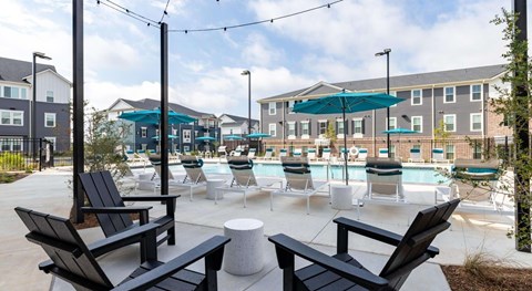 A poolside area with black lounge chairs and a white table.