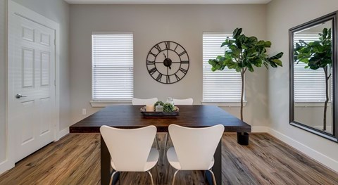 A dining room with a wooden table and white chairs.