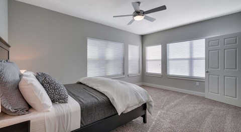 A bedroom with a bed, pillows, and a ceiling fan.
