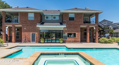 A large brick house with a pool in front.