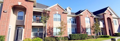 A row of red brick houses with green trees in front.