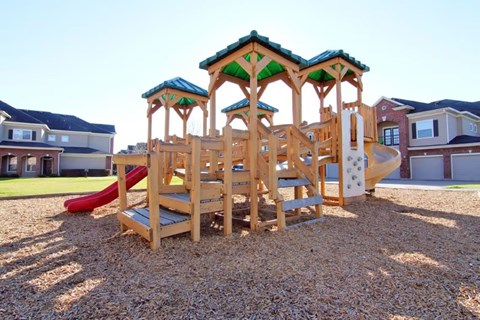 A wooden playground structure with a red slide.