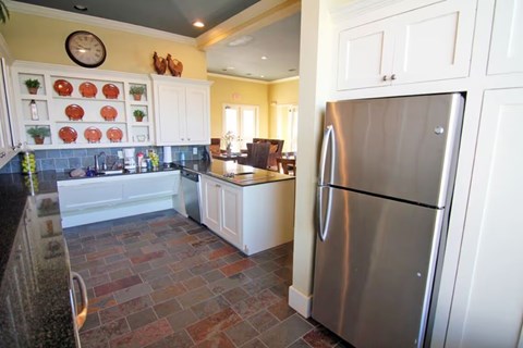 A kitchen with a stainless steel refrigerator and white cabinets.