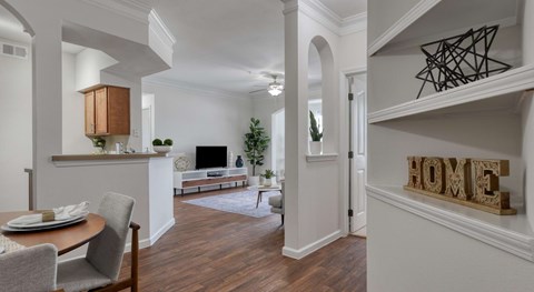 A dining room with a table set for two and a sofa in the background.
