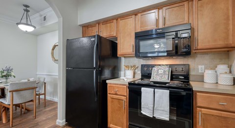 A black refrigerator and microwave in a kitchen with wooden cabinets.