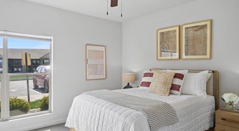 A bedroom with a large bed and a window overlooking a parking lot.