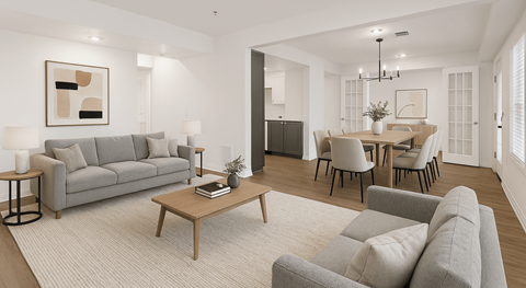 A modern living room with a grey sofa, a wooden coffee table, and a dining table set up with chairs.