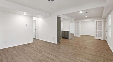 A spacious room with wooden flooring and white walls.