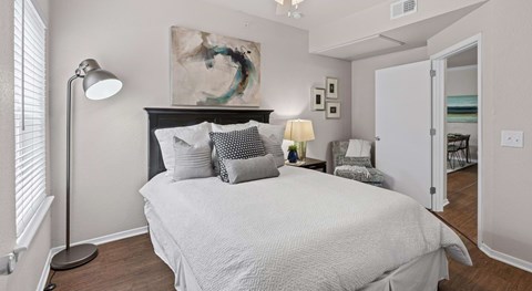 A bedroom with a large bed, a lamp, and a painting on the wall.