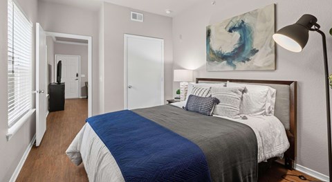 A bedroom with a bed, a lamp, and a painting on the wall.