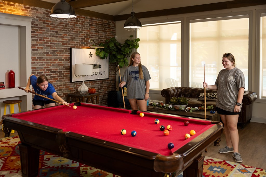 Three People Playing in Game Room With Pool Table at Midtown Sam Houston Apartments, Huntsville, 77340