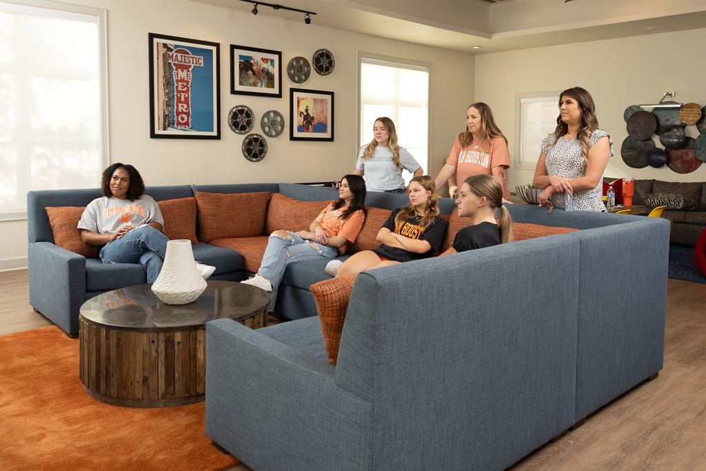 A group of women are sitting on a couch in a living room at Midtown Sam Houston Apartments, Huntsville
