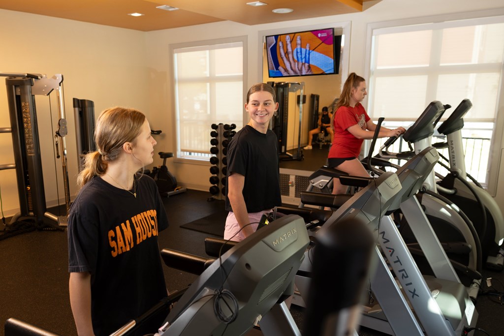 Women's are working out on treadmills in a gym at Midtown Sam Houston Apartments, Huntsville, Texas