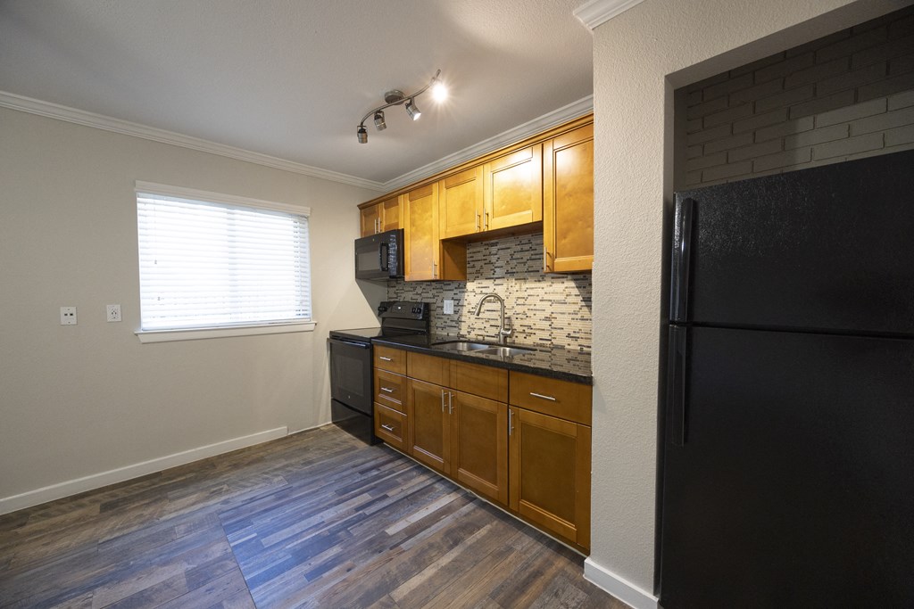 a kitchen with wooden cabinets and a black refrigerator