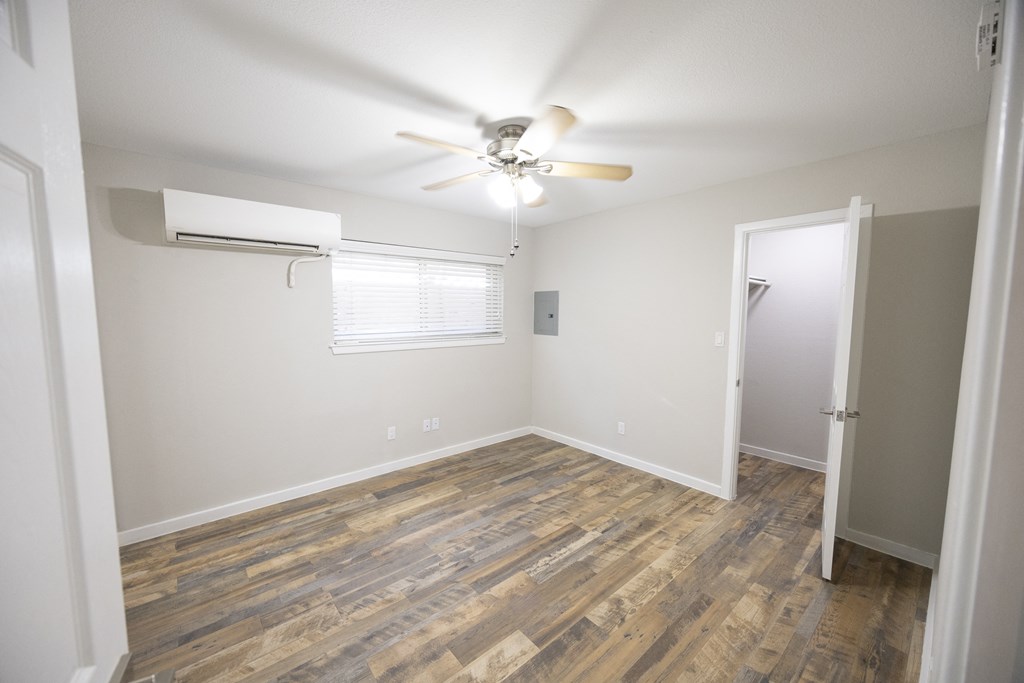 an empty living room with wood flooring and a ceiling fan