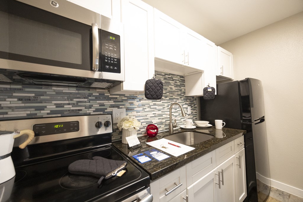 a kitchen with black appliances and white cabinets and a granite counter top