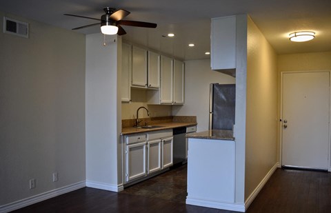 A kitchen with white cabinets and a fan on the ceiling.
