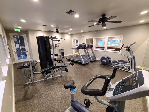 a home gym with exercise equipment and a ceiling fan