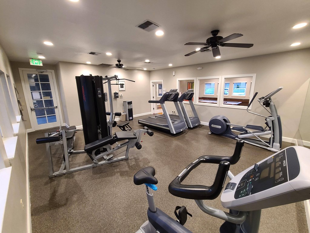 a home gym with exercise equipment and a ceiling fan