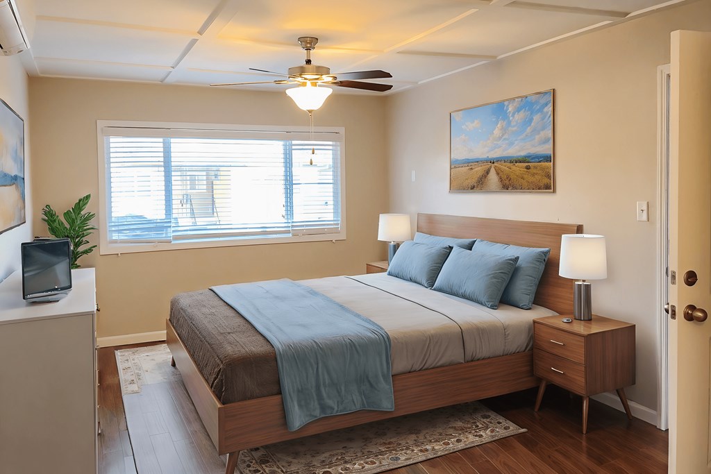 A bedroom with a bed, nightstand, and a painting on the wall.