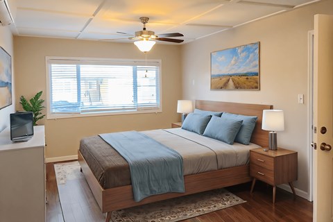 A bedroom with a bed, nightstand, and a painting on the wall.