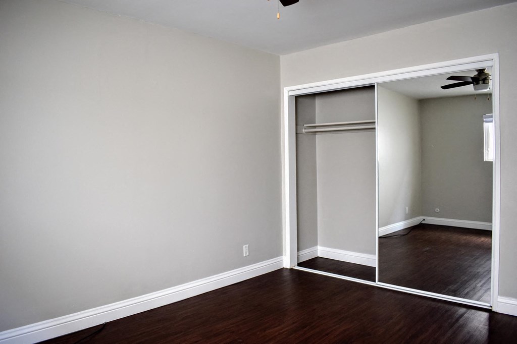 an empty living room with a wood floor and a closet