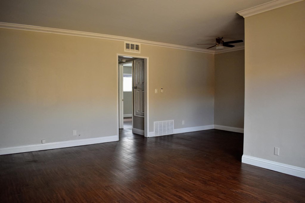 a empty living room with wood floors and a ceiling fan
