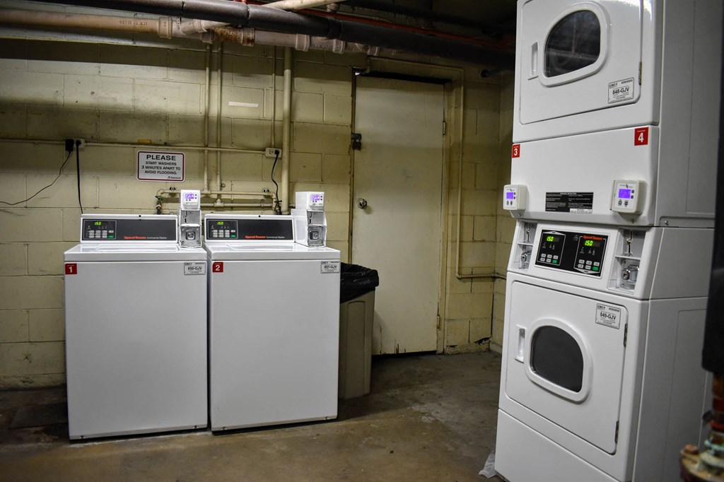 a row of washing machines and dryers in a laundry room