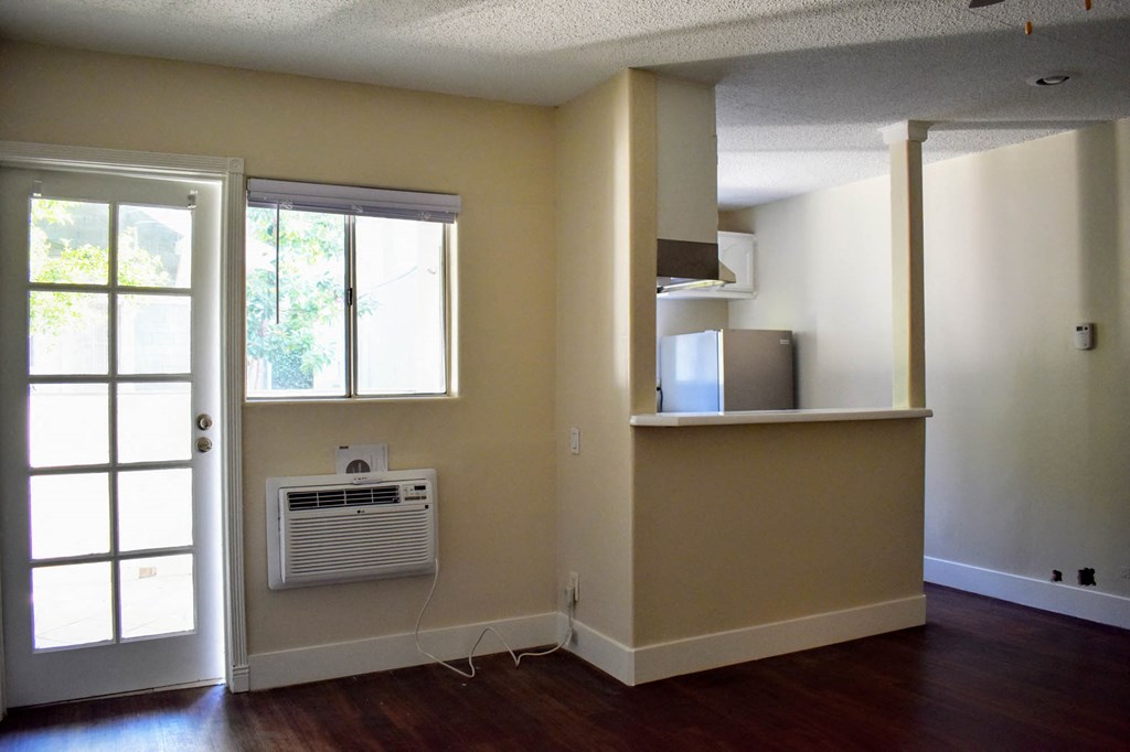 an empty living room with an air conditioner and a window