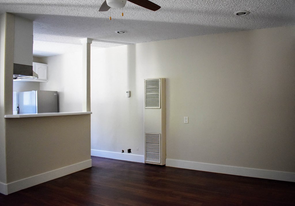 an empty living room with a heater on the wall