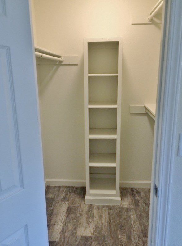 View of walk in closet with built in shelving unit